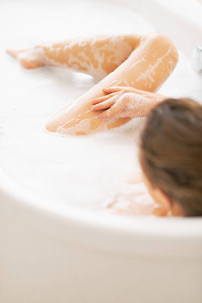 istock young woman washing in bathtub. rear view 472099571