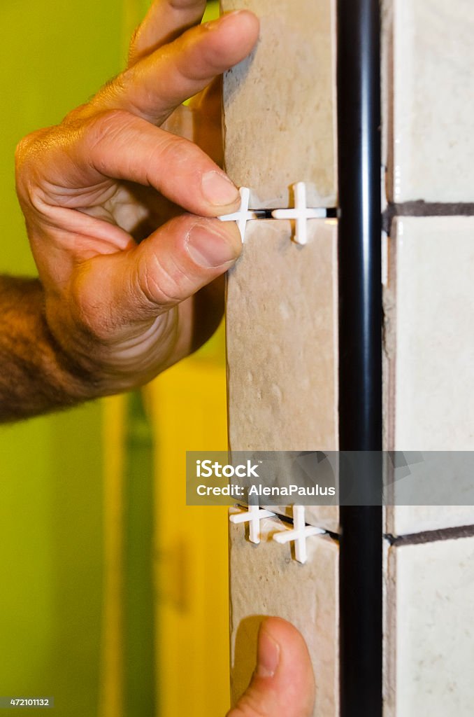 Man placing crosses between tiles for the grout Man placing crosses between the tiles for the grout; close up. Grout Stock Photo