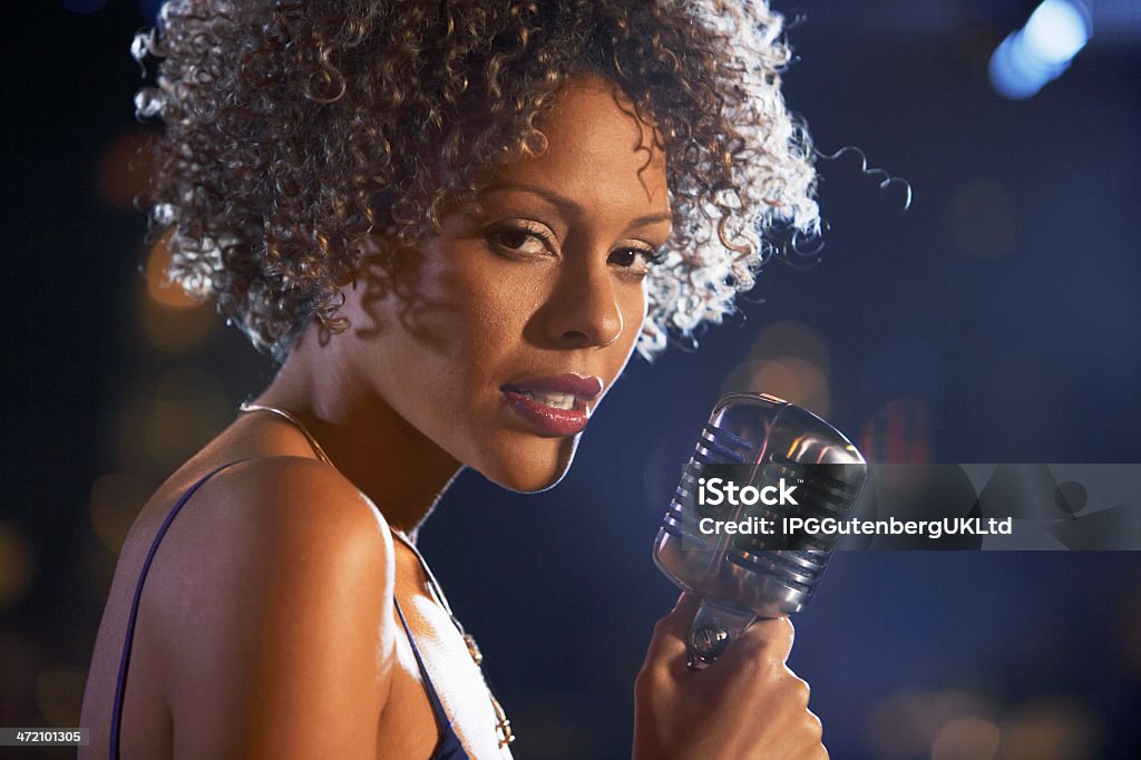 Female singer with natural hair holding old style microphone Closeup of a female jazz singer on stage Singer Stock Photo