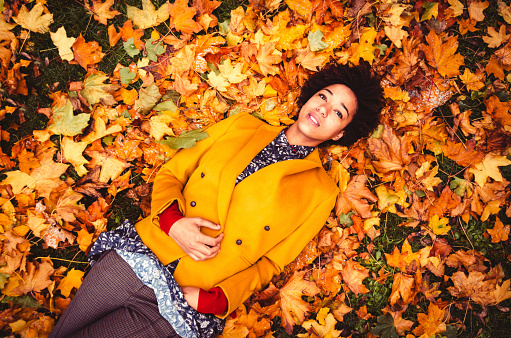 Young Woman Lying Down On Yellow Leaves