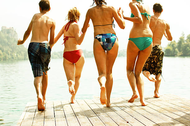 istock Three women and two men jumping into lake 472102637