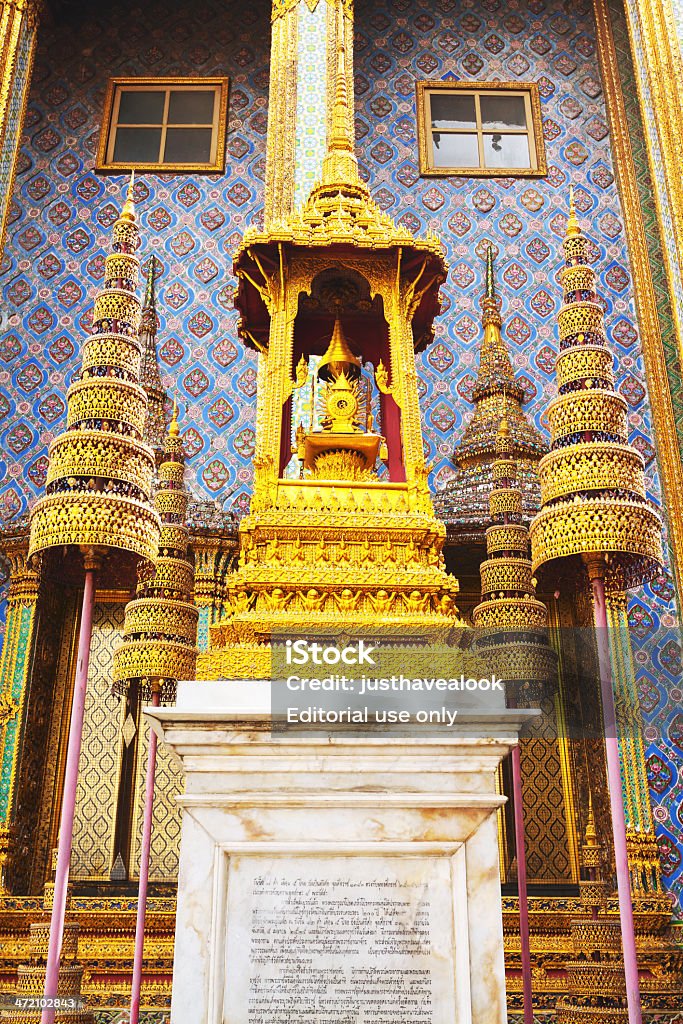 Thai buddhist shrine Bangkok, Thailand - February, 19th 2013: Thai buddhist shrine behind Roal Pantheon in Wat Phra Kaeo. Shrine is surrounded by four lantern like elements. Below is some text on marble block. Architectural Column Stock Photo