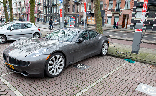Amsterdam, The Netherlands - December 26, 2013: A Fisker Karma sportscar being charged at an Oplaadpunt (EV charging station) of \