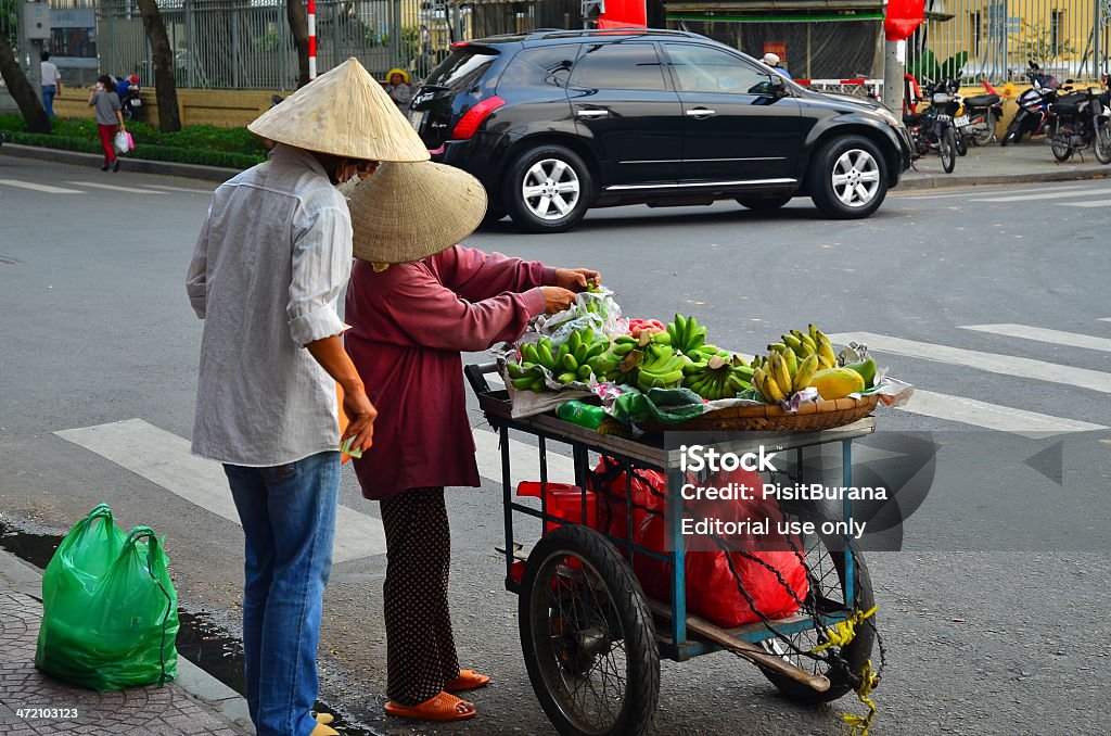 Vietnamese woman selling banana Ho Chi Minh City, Vietnam - October 31, 2013: Woman selling banana from her bicycle to her customer along the busy street Adult Stock Photo