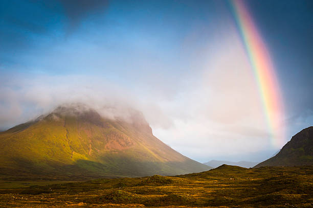 Sunset light and vibrant rainbows on the heathered slopes and misty peaks of the Red Cuillin mountains in this dramatic landscape vista across the Isle of Skye, Scotland. ProPhoto RGB profile for maximum color fidelity and gamut.