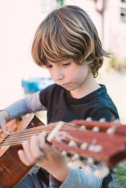 istock Blond little boy playing spanish guitar 472105054