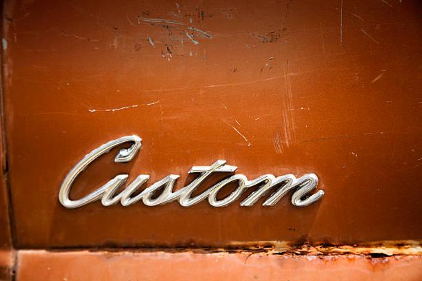 Canton, TX, USA - May 1, 2013:  Metal 'Custom' sign in script on a classic, rusted car body found at a flea market in Canton, Texas, USA. Orange, rust color paint.