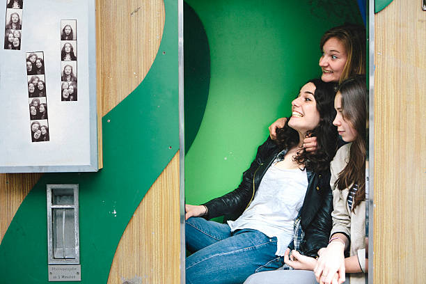 tres mujeres jóvenes juntos en cabina de fotos haciendo caras - photo booth fotografías e imágenes de stock