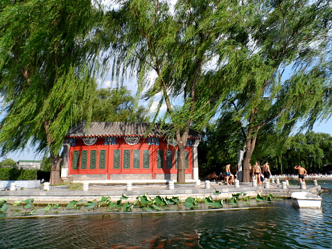 Beijing, China - July 5, 2013: People swim in the lake of Houhai. Some take a break on the ground. Houhai is a famous lake located in the northwest part of Beijing, China. It is surrounded by old-style local residences, Hutongs and Courtyard. This area is also known for its nightlife with many popular restaurants, bars, and cafes.