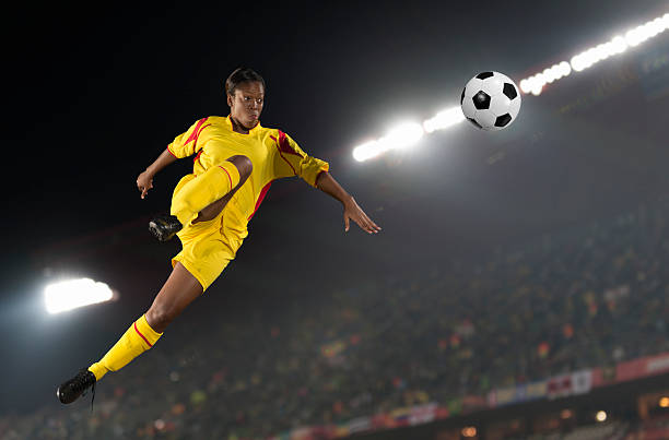 Women's Soccer Female soccer player in action during a floodlit match. Composite image. womens soccer stock pictures, royalty-free photos & images