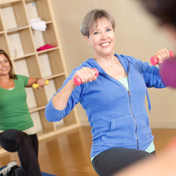 istock Mature adult woman in exercise class using weights 472106907
