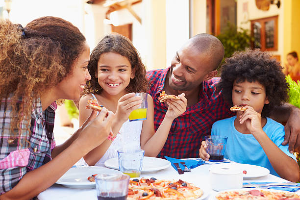 família comer a refeição no restaurante ao ar livre em conjunto - pizza eating african descent lunch imagens e fotografias de stock