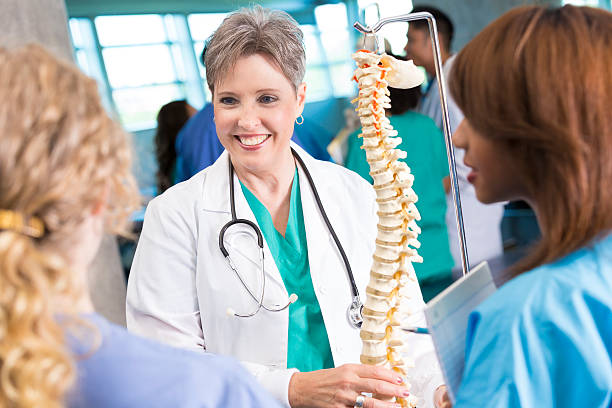 istock Senior medical or nursing professor teaching students with spine model 472110263