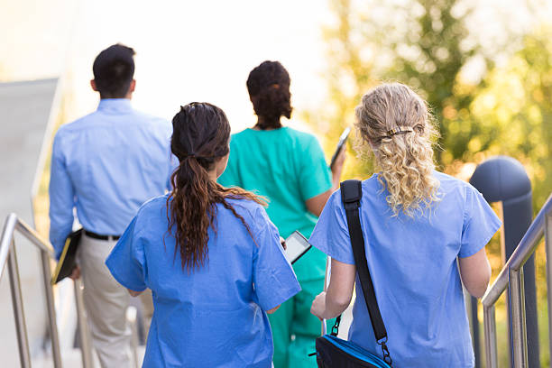 os médicos e enfermeiras a caminhar para a turma no campus universitário - medical student healthcare and medicine book education imagens e fotografias de stock