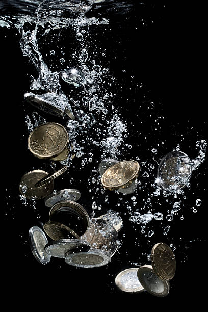 istock Euro coins falling down to water 472113072