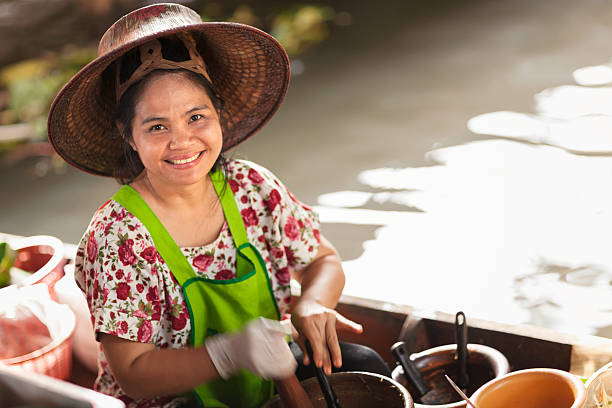 February 7, 2009. Bangkok, Thailand.\nWoman selling fruits at the floating market Damnoen Saduak. Damnoen Saduak floating market is one of Bangkok's top tourist destinations.