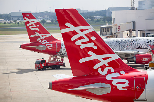 Bangkok, Thailand - November 26, 2013: Row of Air Asia airplanes by the terminal building at the Don Mueang airport. Air Asia is a Malaysian low-cost airline with headquarters in Kuala Lumpur, Malaysia.