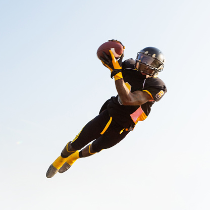 Professional football player jumping to catch ball during game