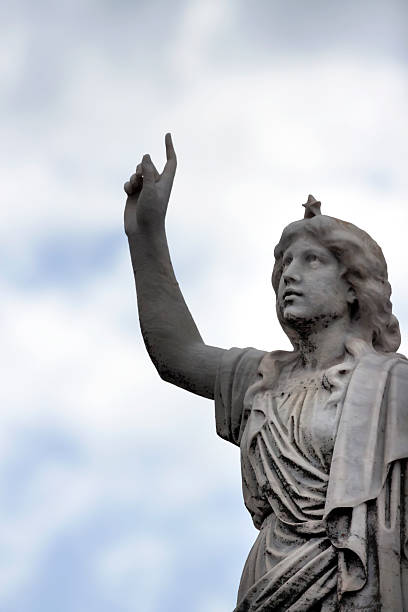 istock Statue of angle pointing up, against sky background, copy space 472114787