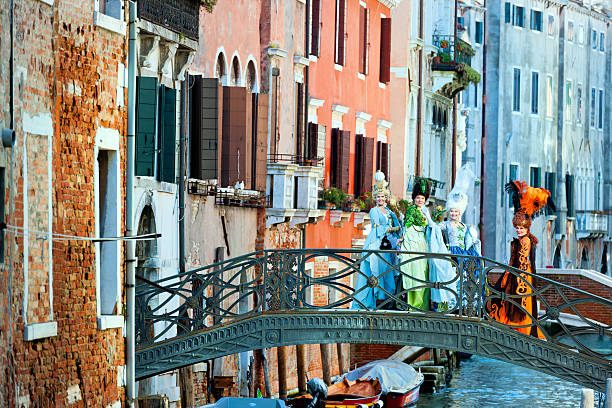 Venice, Italy - February 8th, 2013: Beautiful female masks posing on metal bridge Fondamenta dei Felzi during 2013 Carnival celebrations.