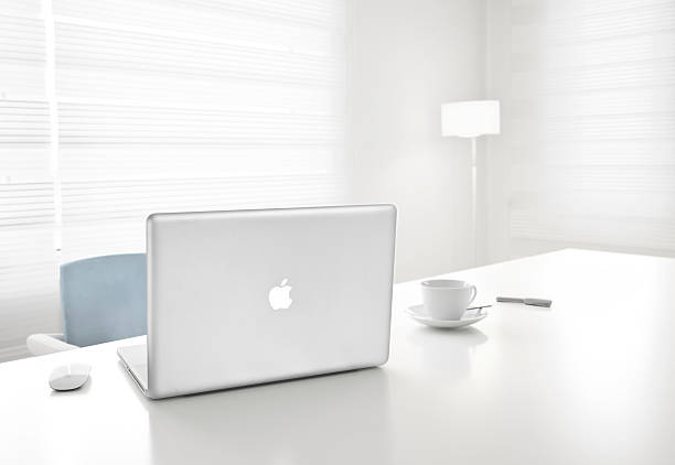 Apple 17-inch MacBook Pro and magic mouse in office stock photo