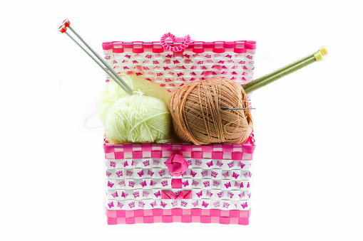 Colorful yarn balls in the basket isolated on white background