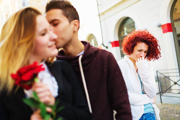 Lost Love Young crying woman on the street saw her boyfriend with other woman. three way kiss stock pictures, royalty-free photos & images