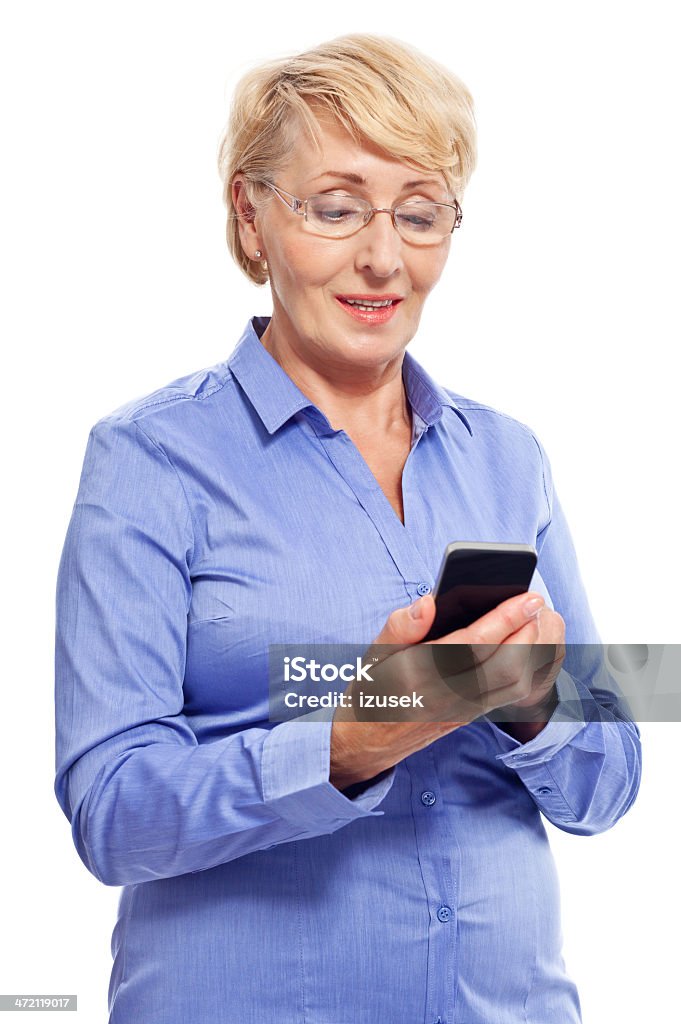 Senior businesswoman with smart phone Portrait of senior businesswoman using a smart phone. Studio shot, white background. White Background Stock Photo