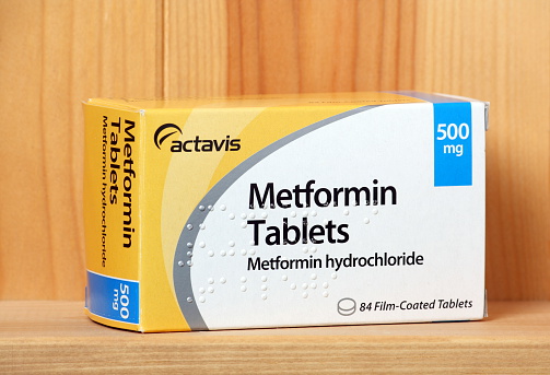 Bracknell, England - January 14, 2014: A box of Metformin tablets produced by the pharmaceutical company Actavis, on a wooden shelf. Metformin is an oral treatment for type 2 Diabetes.
