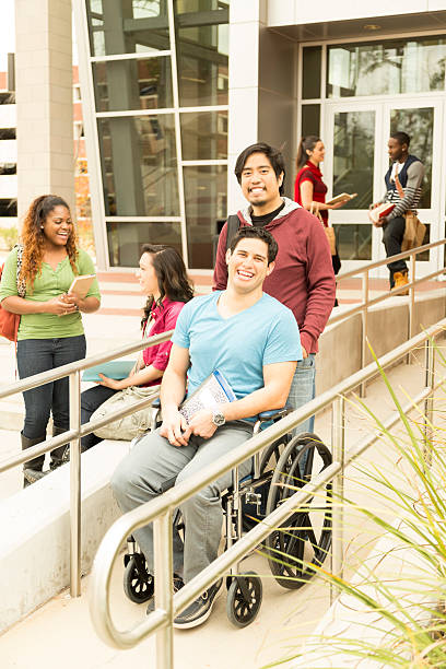 istock Education: Disabled student helped down wheelchair ramp. College campus. 472120749