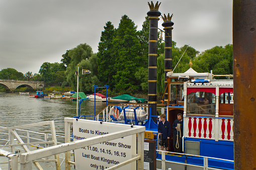 London, United Kingdom - July 12, 2013: This is a view of the front of a Thames River Cruiser at the Richmond boarding point on a journey to Hampton Court Palace. There are 2 of the cruisers staff coming out of the cabin door. The company is Turks River Cruises.