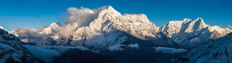 Warm, late afternoon sunlight illuminating the snow capped peaks, dramatic rocky pinnacles and high altitude Himalaya ridges of Thamserku (6608m), Kang Tega (6779m) and Kusum Kanguru (6367m) towering over the picturesque mountain scenery of the Khumbu region deep in the Everest National Park, Nepal. ProPhoto RGB profile for maximum color fidelity and gamut.