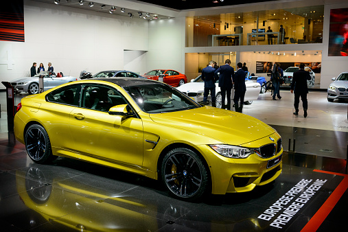 Brussels, Belgium - January 14, 2014: BMW M4 coupe sports car on display at the 2014 Brussels motor show. The M4 is the M Performance version of the BMW 4-series. People in the background are looking at the cars.