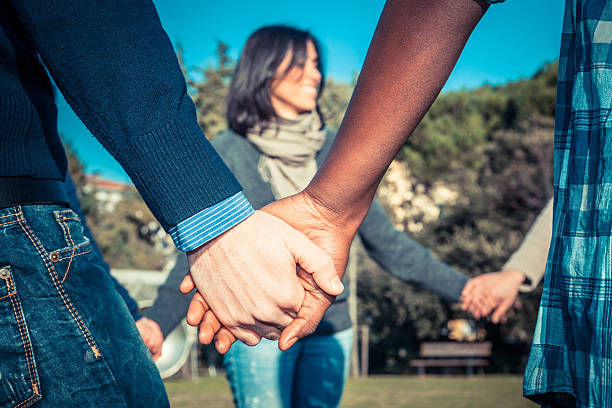 Young people holding hands in a circle at the park