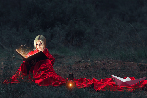 Mystery Girl reading magic book in a forest.