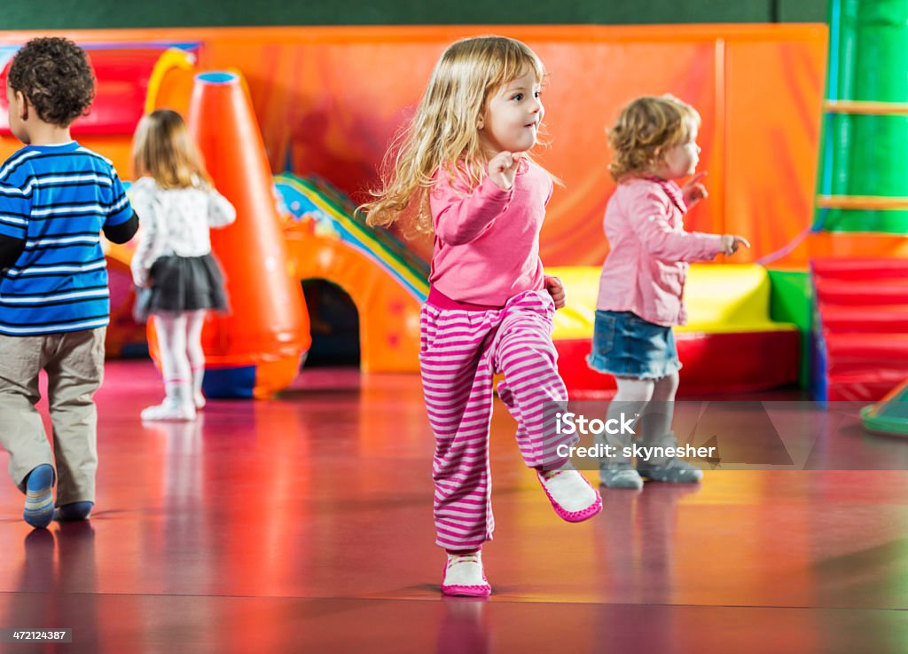Children dancing. Cute kids dancing in the playroom. Focus is on girl in the foreground.   Preschool Stock Photo