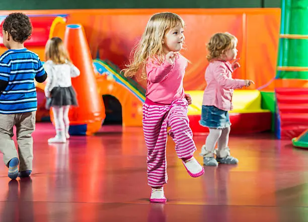 Cute kids dancing in the playroom. Focus is on girl in the foreground.  