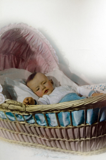 An old 1941  image of a bay sleeping. A black and white photo colored by hand with oil paints. 