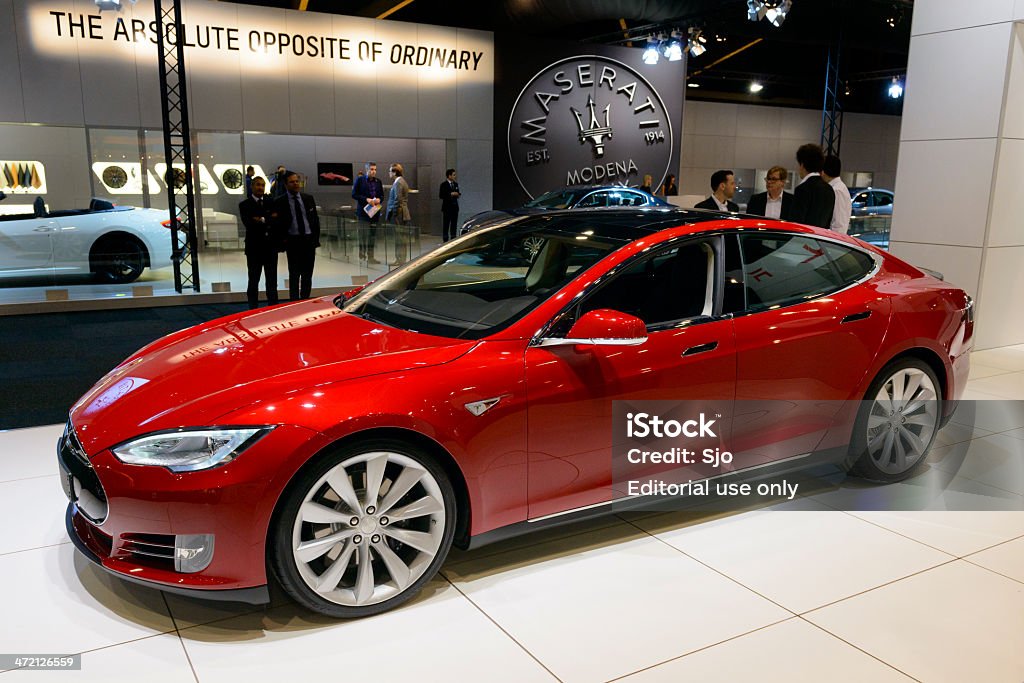 Tesla Model S Brussels, Belgium - January 14, 2014: Red Tesla Model S full-sized electric five-door hatchback on display at the 2014 Brussels motor show. People in the background are looking at the cars. Electric Car Stock Photo