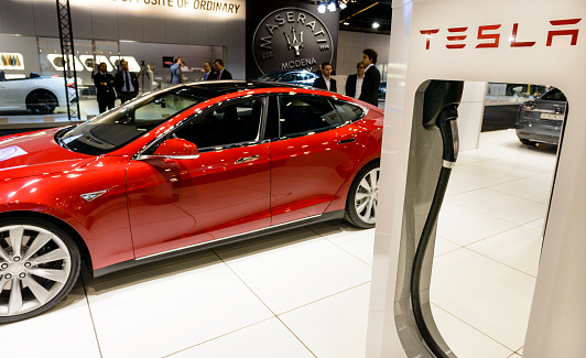 Brussels, Belgium - January 14, 2014: Red Tesla Model S full-sized electric five-door hatchback on display at the 2014 Brussels motor show. People in the background are looking at the cars.