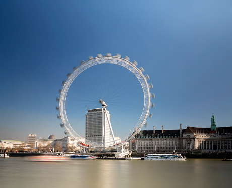 London, UK - February 19, 2013: Ships moving in front of the London Eye ferris wheel on the south side of the River Thames