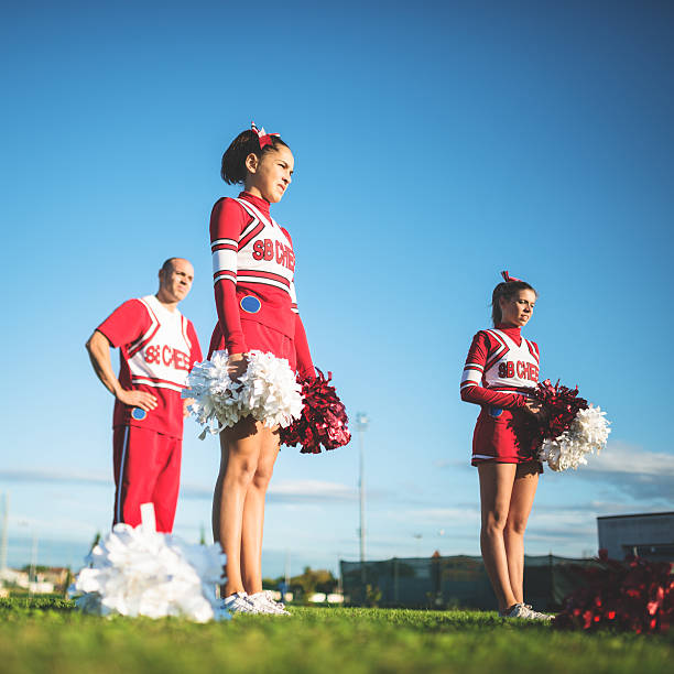 istock cheerleaders preparing to jump with the coach behind 472127163
