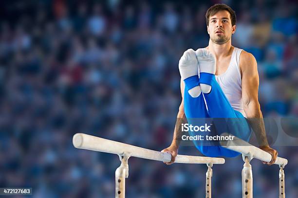 Male Gymnast Performing Routine On Parallel Bars Stock Photo - Download Image Now - Artistic Gymnastics, Horizontal Bar, Men