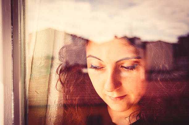 istock Young woman looking out window 472128031