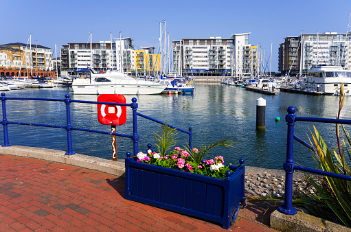 Eastbourne, UK - July 7, 2013: The location is the Sovereign Harbour Marina, on the South Coast of England at the seaside resort of Eastbourne in Sussex. Boats are moored surrounded by flats and apartments. There are motor boats, fishing boats and sailing yachts at their moorings, It is a hot sunny day in July, Summer and there is a clear blue sky. The Marina is popular with tourists visitors and leisure boaters.