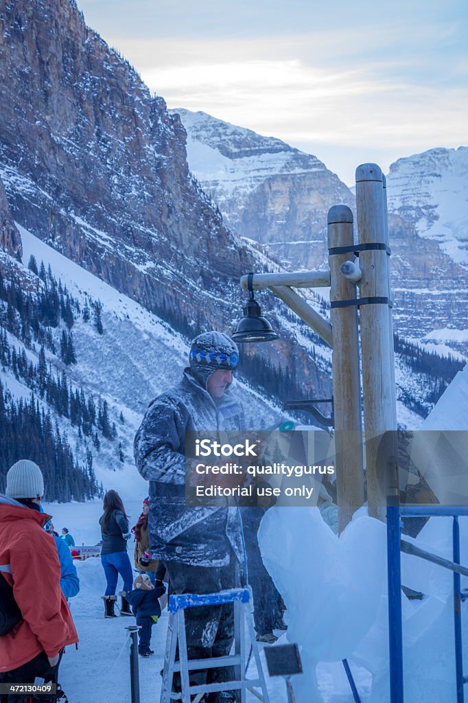 Sculpting at Banff Lake Louise Ice Magic Festival 2014 Lake Louise, Canada- January 18, 2014:  An ice sculptor carves a tall block of ice with a power tool during the Lake Louise Ice Magic Festival , an annual event. Alberta Stock Photo