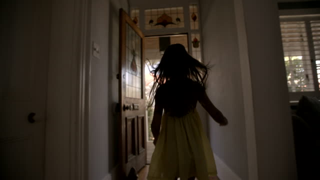 Little girl running happily to an open front door