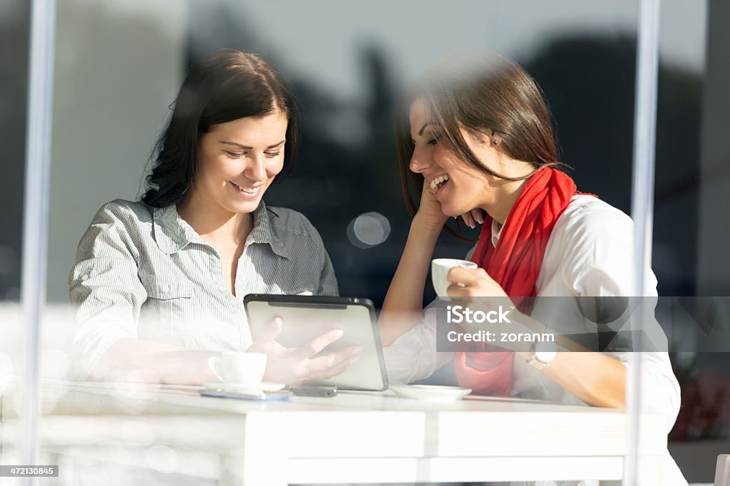 Coffee time Two women using digital tablet in cafe. drinking coffee Adult Stock Photo