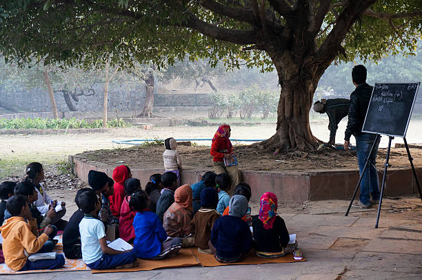 Delhi,India: 4th Jan 2014 - Poor children being taught in an open air classroom by volunteers. Classes like this (madrasa) are often held at the hauz khas village in Delhi India. This is to impart basic education to those who are unable to afford traditional schools.