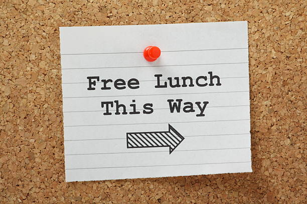 Free Lunch This Way The phrase Free Lunch This Way typed on a piece of lined paper and pinned to a cork notice board free of charge stock pictures, royalty-free photos & images